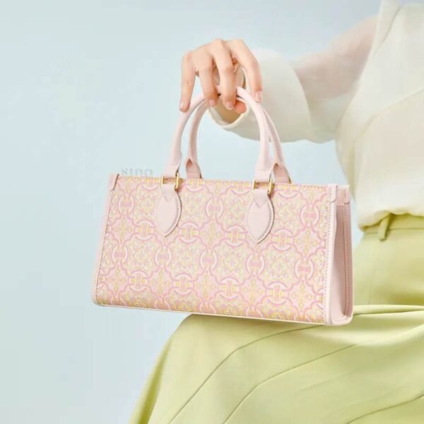 song-brocade-leather-handbag-pink-gold-dingsheng-motif-model-sitting-knee-handheld song-brocade-leather-handbag-pink-gold-dingsheng-motif-model-sitting-knee-handheld